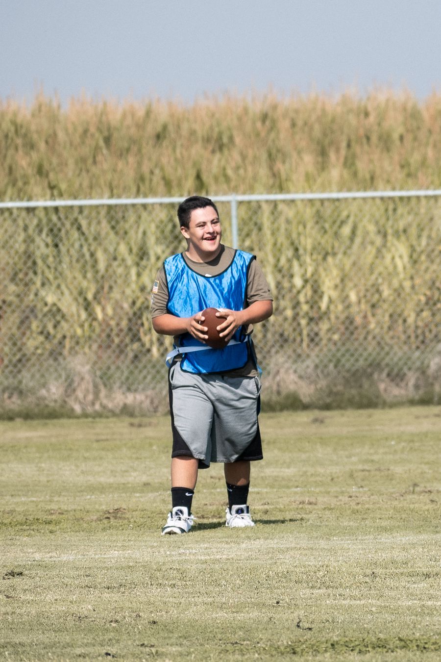 A smiling athlete holds a football on a grass field